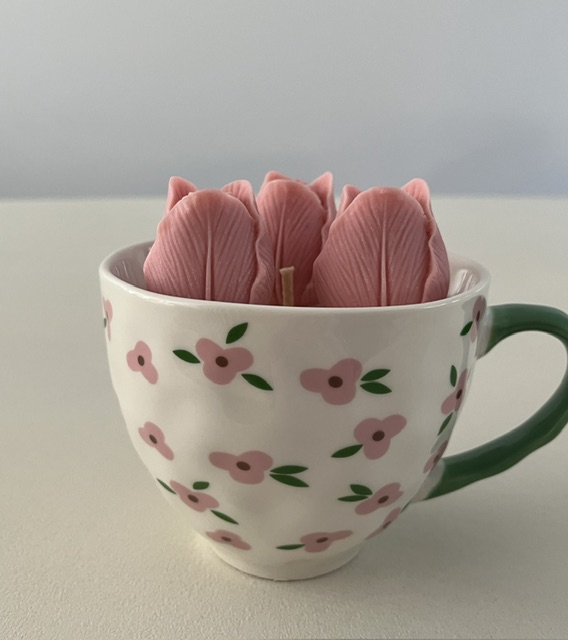 Vrolijke kaars in een bloemrijke mok